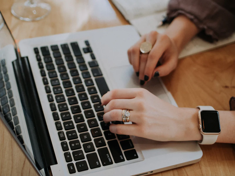 Hands working on a laptop on a wooden table
